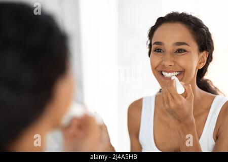 Schöne Junge Dame, Die Den Spiegel Anschaut Und Feuchtigkeitsspendenden Lippenbalsam Anwendet Stockfoto