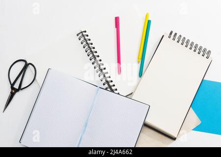 Viele Notizbücher auf Federn, mehrfarbiger Papier: Blau, rot, grün, Gold, Stifte und Scheren. Bürokonzept. Für Text platzieren Stockfoto