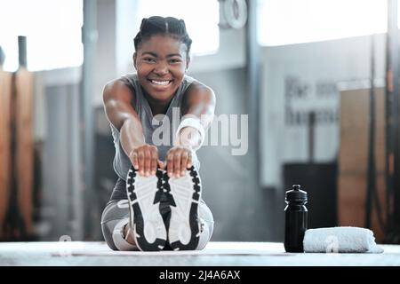 Lassen Sie das Bedauern auf gestern. Porträt einer jungen, schönen Frau, die Dehnübungen macht und im Fitnessstudio trainiert. Stockfoto