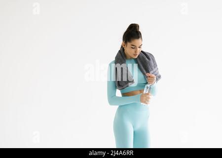 Ruhezeit. Sportliche Mädchen mit Handtuch auf Schultern Wasser trinken. Foto von körperliche Fitness Model isoliert auf weißem Hintergrund. Gesundheitskonzept. Stockfoto