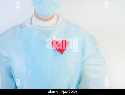 Ärztin in einem schützenden blauen Anzug mit rotem Herz auf weißem Hintergrund. Stockfoto