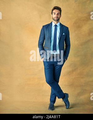 Der Erfolg ist golden. Studioaufnahme eines hübschen jungen Geschäftsmannes, der vor goldenem Hintergrund posiert. Stockfoto