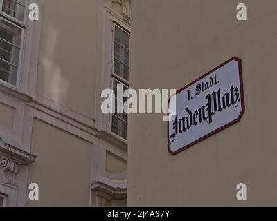 Nahaufnahme des Straßenschildes an der Fassade eines alten Gebäudes im Zentrum der historischen Innenstadt von Wien, Österreich. Text auf Schild: Jüdischer Platz. Stockfoto