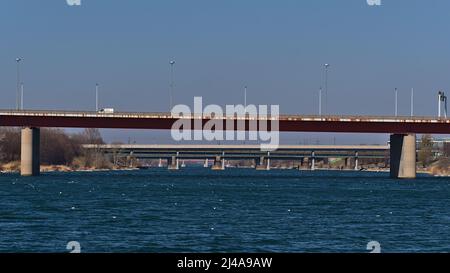 Abnehmende Perspektive der blauen Wasseroberfläche der Donau im Zentrum von Wien, Österreich mit mehreren Straßenbrücken in Folge an sonnigen Tagen. Stockfoto