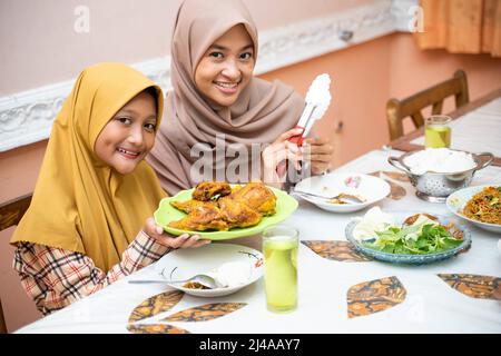 muslimische Mutter serviert etwas Essen für das Familienessen Stockfoto