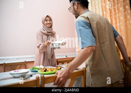 muslimische Mutter serviert etwas Essen für das Familienessen Stockfoto