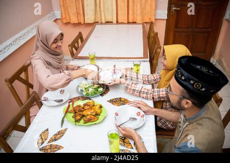 muslimische Mutter serviert etwas Essen für das Familienessen Stockfoto