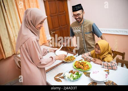 muslimische Mutter serviert etwas Essen für das Familienessen Stockfoto