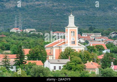Traditionelles Dorf mit Hütten und einer Kirche mit Glockenturm im Zentrum. Das Hotel liegt in einer natürlichen Umgebung mit grünen Bäumen in Kroatien. Stockfoto