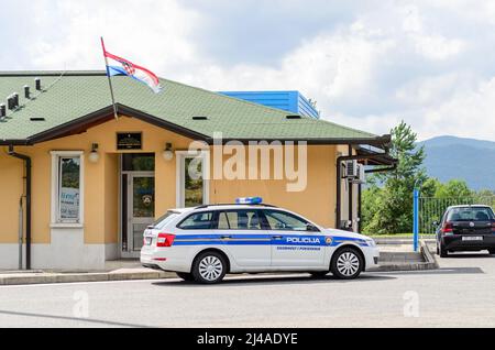 Das Fahrzeug der kroatischen Polizei patrouilliert die Grenzen zwischen Kroatien und Slowenien. Geparkt vor einer traditionellen Polizeistation mit der winkenden Flagge. Stockfoto