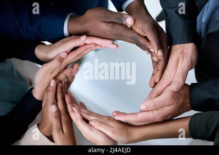 Alles kann erreicht werden, wenn wir zusammenarbeiten. Ausgeschnittene Aufnahme einer Gruppe von nicht erkennbaren Geschäftsleuten, die sich solidarisch in die Hände schlossen. Stockfoto