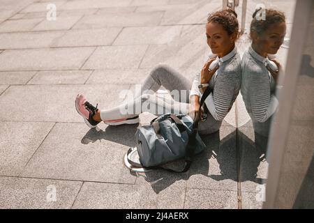 Gesunde sportliche Frau, die nach dem Training in der Stadt eine Pause einlegen muss Stockfoto