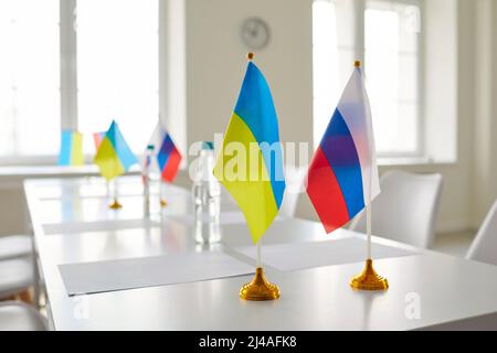 Tisch mit Flaggen der Russischen Föderation und der Ukraine im leeren Raum vor dem Verhandlungstreffen Stockfoto