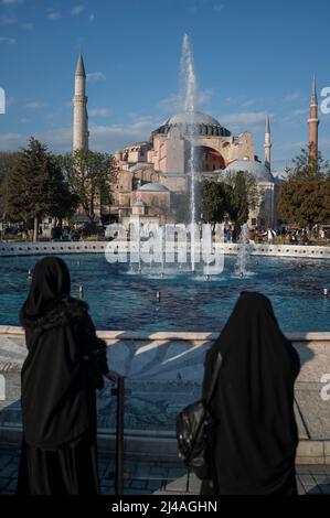 Istanbul, Türkei. 13. April 2022. Zwei Frauen stehen vor einem Brunnen im Sultanahmet Park mit der Hagia Sophia im Hintergrund. Quelle: Arne Immanuel Bänsch/dpa/Alamy Live News Stockfoto