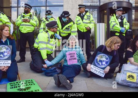 London, England, Großbritannien. 13. April 2022. Polizeibeamte verhindern, dass sich eine Protestierenden auf den Boden kleben kann. Aktivisten des Extinction Rebellion verursachten Chaos im Londoner Hauptquartier des Ölgiganten Shell, wobei sich Dutzende von Demonstranten vor dem Eingang am Boden und mehrere im Gebäude klebten. (Bild: © Vuk Valcic/ZUMA Press Wire) Stockfoto