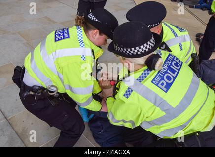 London, England, Großbritannien. 13. April 2022. Polizeibeamte verhindern, dass sich eine Protestierenden auf den Boden kleben kann. Aktivisten des Extinction Rebellion verursachten Chaos im Londoner Hauptquartier des Ölgiganten Shell, wobei sich Dutzende von Demonstranten vor dem Eingang am Boden und mehrere im Gebäude klebten. (Bild: © Vuk Valcic/ZUMA Press Wire) Stockfoto