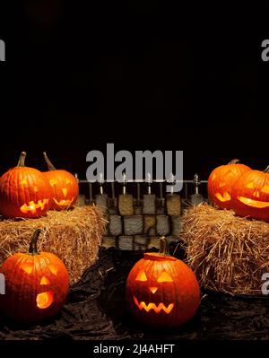 Gruselige Halloween-Szene mit Jack-o-Laternen, Heu und einem gruseligen Zaun Stockfoto