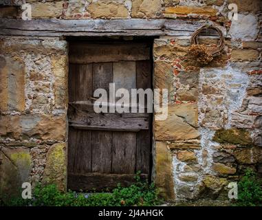 Eine alte Holztür in einem verrottten Haus in Poffabro, einem historischen mittelalterlichen Dorf im Val Colvera Tal in der Provinz Pordenone, Friaul, Italien Stockfoto