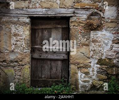 Eine alte Holztür in einem verrottten Haus in Poffabro, einem historischen mittelalterlichen Dorf im Val Colvera Tal, Provinz Pordenone, Friaul. Italien Stockfoto