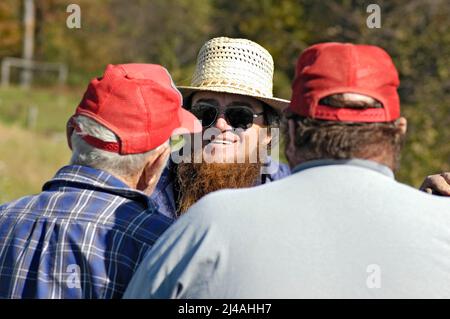 Amische Bauer im Gespräch mit seinem Kollegen Züchter bei einer Auktion Stockfoto