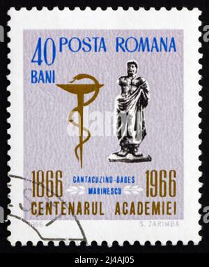 RUMÄNIEN - UM 1966: Eine in Rumänien gedruckte Marke zeigt die Statue des Ovid und das Emblem der Medizinischen Schule, 100 Jahre der Rumänischen Akademie, um 1966 Stockfoto