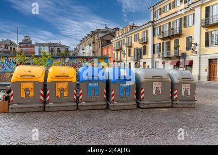Cuneo, Italien - 11. April 2022: Reihe selektiver Abfallsammlungsbehälter auf dem Boves-Platz im historischen Zentrum. Gelb für Papier, blau für Kunststoff, grau Stockfoto