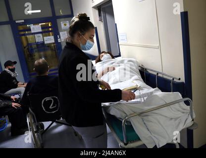 Krakau. Krakau. Polen. ER-Zimmerangestellte untersucht die Krankenakten einer Patientin, die auf der Gurney-Bahre liegt. Stockfoto