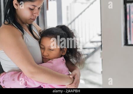 Schöne kleine braune Latina Mädchen umarmt ihre Mutter zärtlich und stolz, sie an ihrer Seite zu haben. Tochter dankt ihrer Mutter für die ganze Liebe Stockfoto