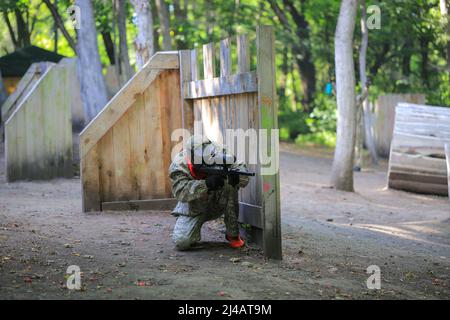 Paintball-Spieler in voller Ausrüstung schießt auf dem Schießstand Stockfoto