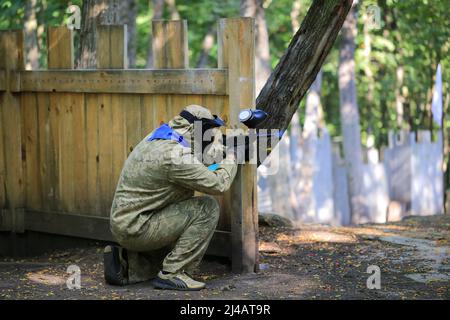 Paintball-Spieler in voller Ausrüstung schießt auf dem Schießstand Stockfoto