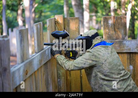 Paintball-Spieler in voller Ausrüstung schießt auf dem Schießstand Stockfoto