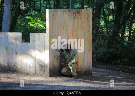 Paintball-Spieler in voller Ausrüstung schießt auf dem Schießstand Stockfoto