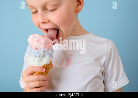 Der Junge leckte Eis schloss seine Augen. Schmutzige Flecken von Eis auf weißen Kleidern. Fleck im täglichen Leben und Reinigungskonzept. Hochwertige Fotos Stockfoto