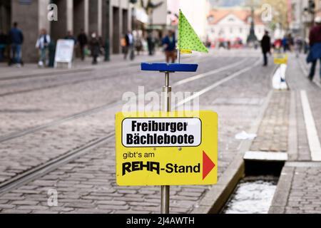 Freiburg, Deutschland - 2022. April: Schild zeigt auf einen Laden, der kleine Holzspielzeugboote verkauft Kinder können auf dem Bach 'Bächle' im Stadtzentrum schweben Stockfoto