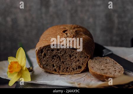 Mad hält Korb mit frisch hausgemachtem Vollkornbrot. Einfaches Kochen von gesundem Brot aus alternativen Mehlen. Stockfoto