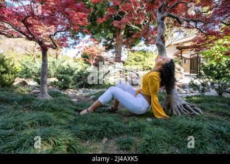 Kraftvolles Porträt einer schönen jungen schwarzen Frau unter japanischem Ahornbaum Stockfoto