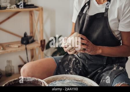 Unverkennbare weibliche Potter-Meisterin bereitet Tonhaufen vor, um in ihrem Keramikstudio einen Topf auf einem Töpferrad zu kreieren Stockfoto