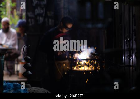 MARRAKESCH, MAROKKO - 21. NOVEMBER; 2018 Metallarbeiter in der Medina mit einem Café im Hintergrund Stockfoto
