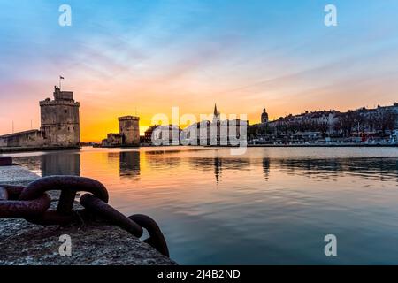 Panoramablick auf den berühmten alten Hafen von La Rochelle bei Sonnenuntergang. Metallkette im Vordergrund Stockfoto