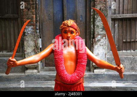 Ein junger Hindu-Anhänger mit seiner in roter Farbe gemalten corp nimmt an einer Prozession Teil, die Schwerter im Rahmen der jährlichen Lal Kach (Rotes Glas) fes hält Stockfoto