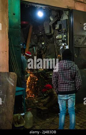 MARRAKESCH, MAROKKO - 21. NOVEMBER; 2018 Shopper beobachten einen Metallarbeiter in der Medina Stockfoto