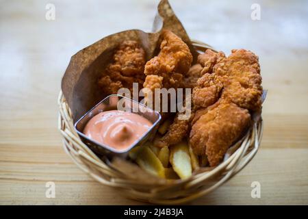 Knusprig gebratene Kentucky Chicken Wings in einem Korb, mit Pommes frites und Sauce. Stockfoto