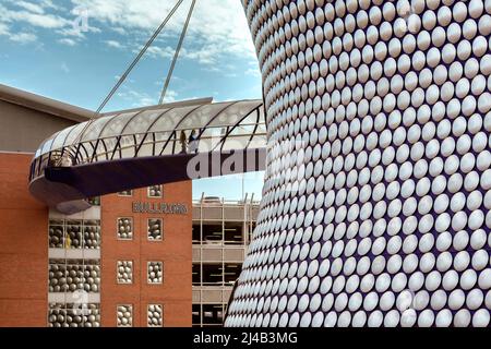 Die Menschen überqueren die geschlossene Brücke vom Parkplatz zum Selfridges-Geschäft mit seiner ikonischen silbernen Scheibenverkleidung im Stadtzentrum von Birmingham. Stockfoto