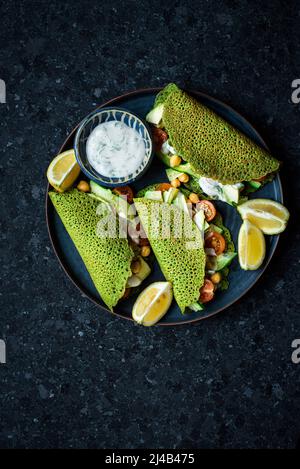Gefüllte grüne Pfannkuchen, verpackt und mit Salat serviert Stockfoto