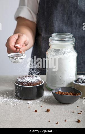 Puderzucker auf einen Schokoladen-Souffle stauben Stockfoto