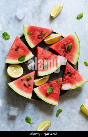 Scheiben Wassermelone mit Zitronen- und Minzblättern Stockfoto