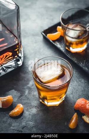 Ein hintergrundbeleuchteter Becher mit alkoholischem Whisky auf grauem Hintergrund Stockfoto