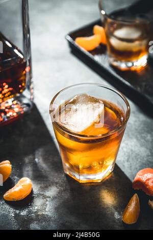 Ein hintergrundbeleuchteter Becher mit alkoholischem Whisky auf grauem Hintergrund Stockfoto