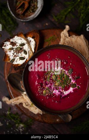 Eine Schüssel Rote-Beete-Suppe, garniert mit Rahm, Dill, Kürbis und Chiasamen. Stockfoto