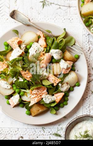 Salatplatte mit pochiertem Slalmon, gekochten Kartoffeln, Erbsen, Lämmersalat und cremigem Dilldressing. Stockfoto